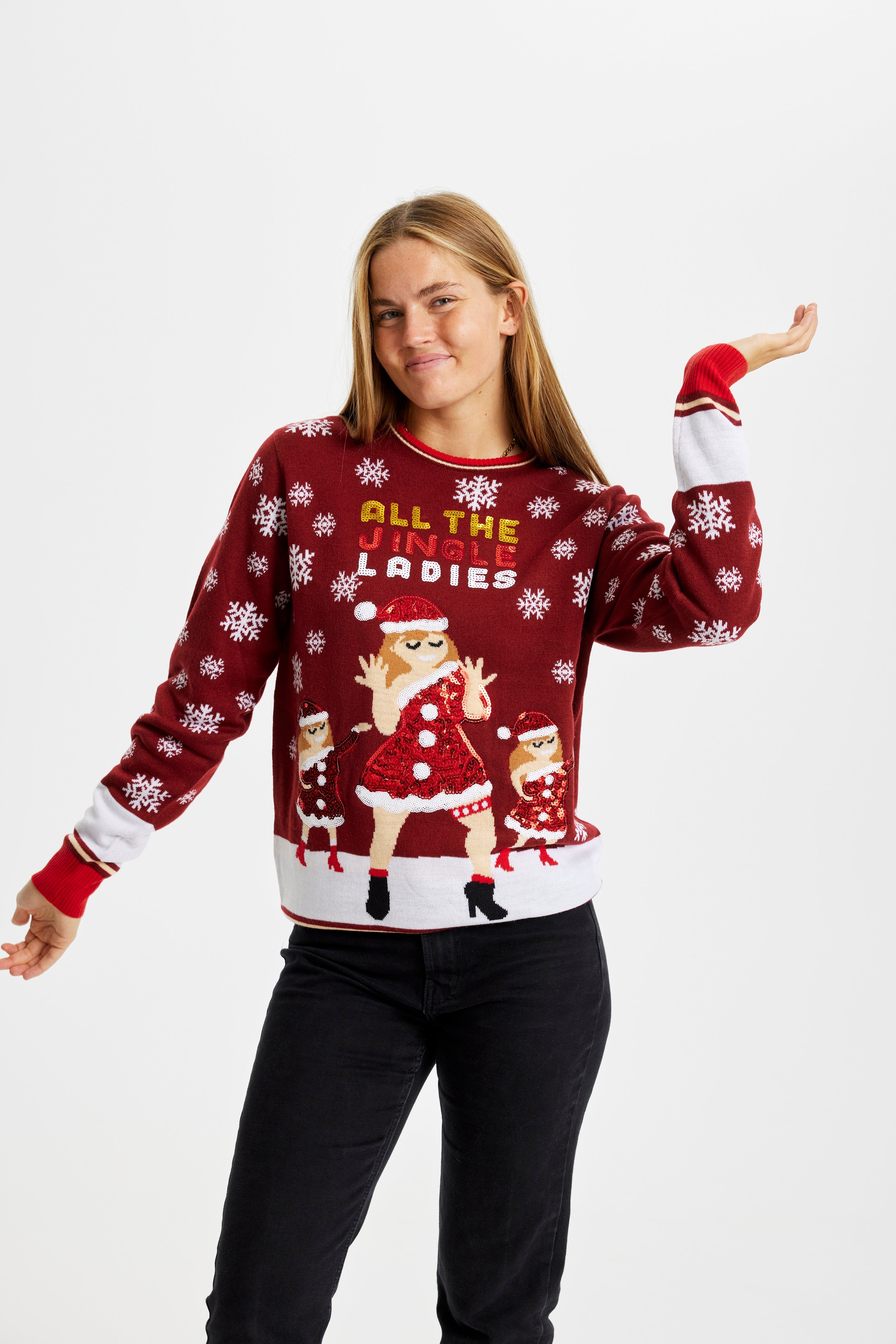 En glad dame poserer i en rød julesweater med en dansende julepige og snefnug.